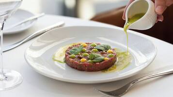 Un piatto di tartare di manzo con salsa che viene versata sopra.