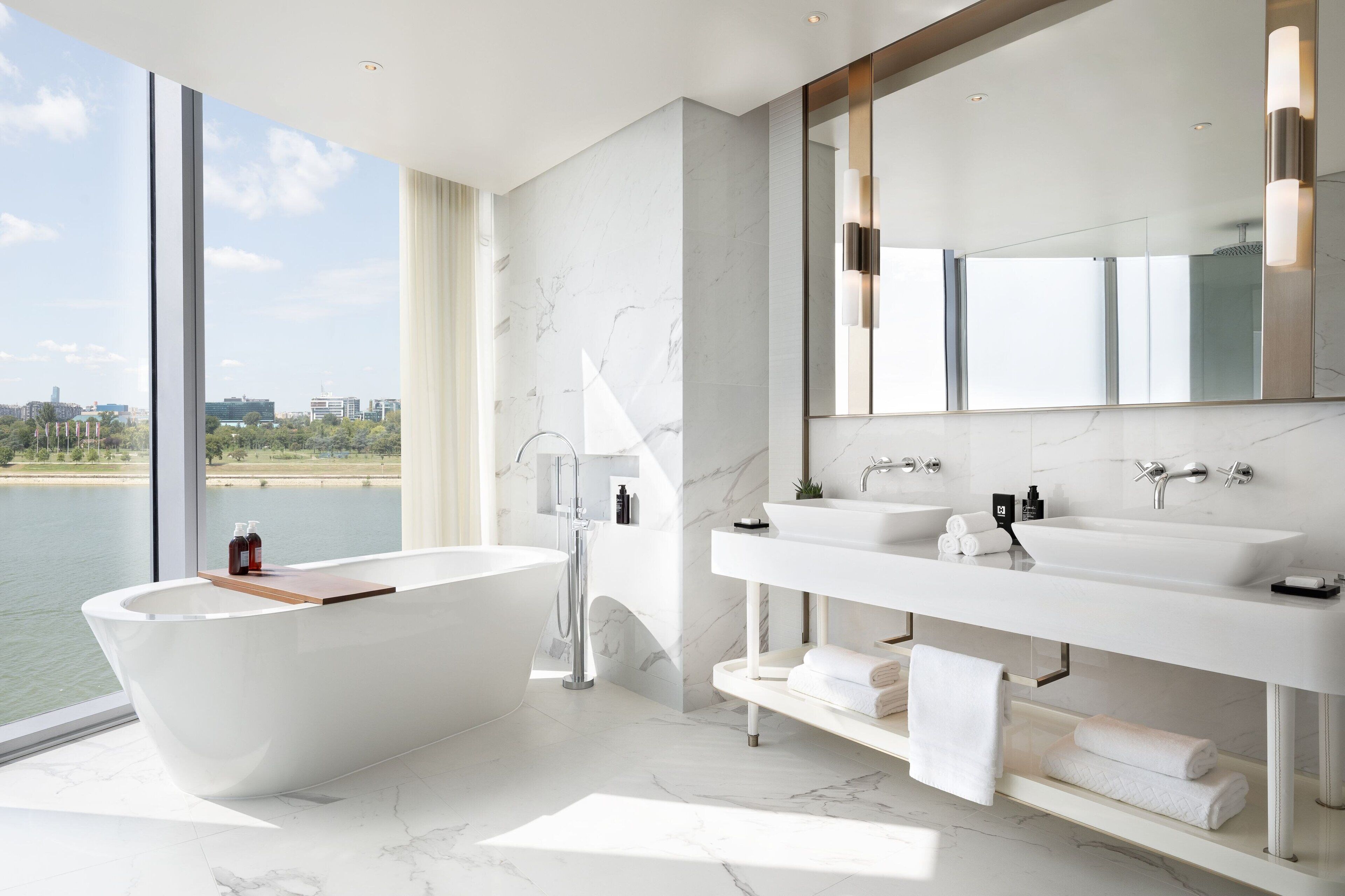 Une salle de bain moderne avec une baignoire sur pieds, deux vasques et un grand miroir.