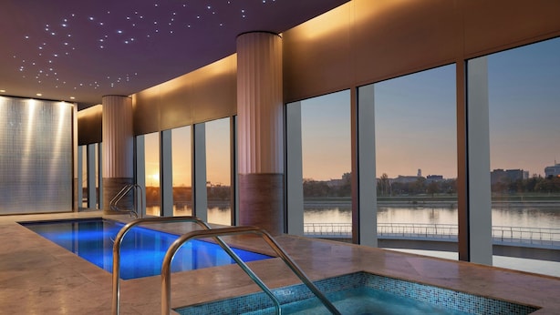 A modern indoor pool area with clear views of a cityscape and a river. - The St. Regis Belgrade (Belgrade)
