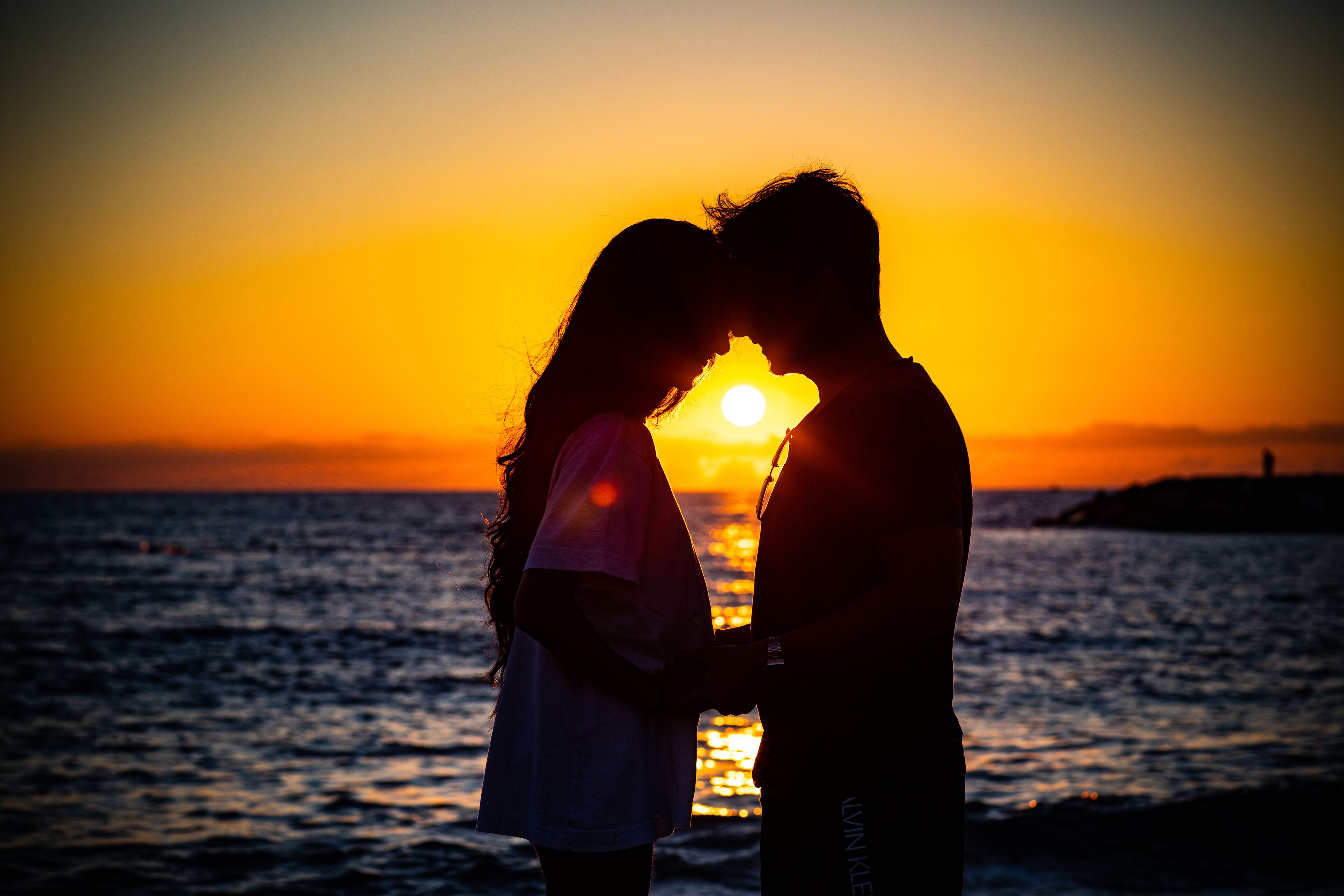 A couple embracing at sunset by the sea.