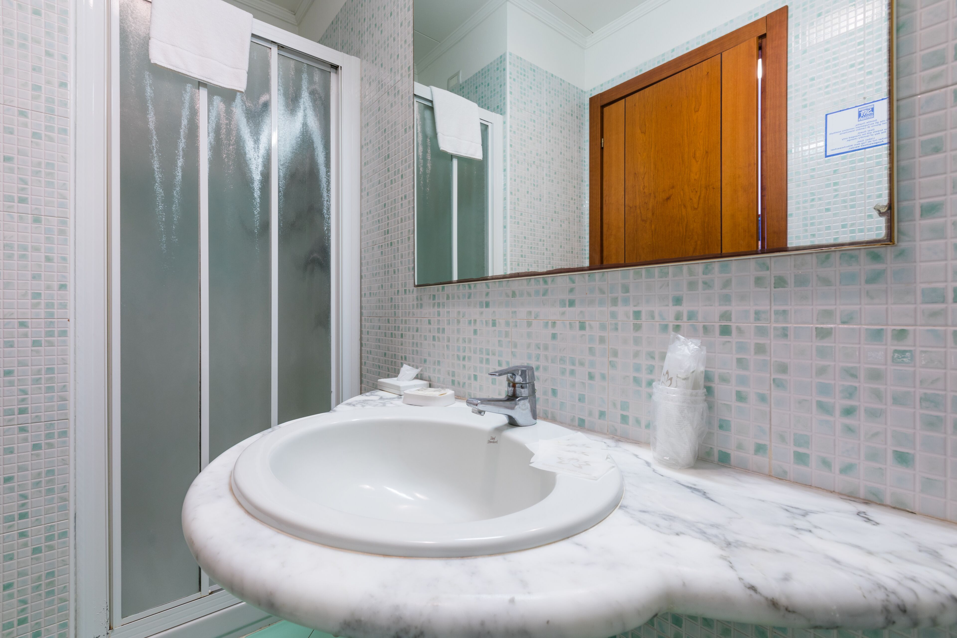 A bathroom with a white sink, a mirror, and a shower enclosure.