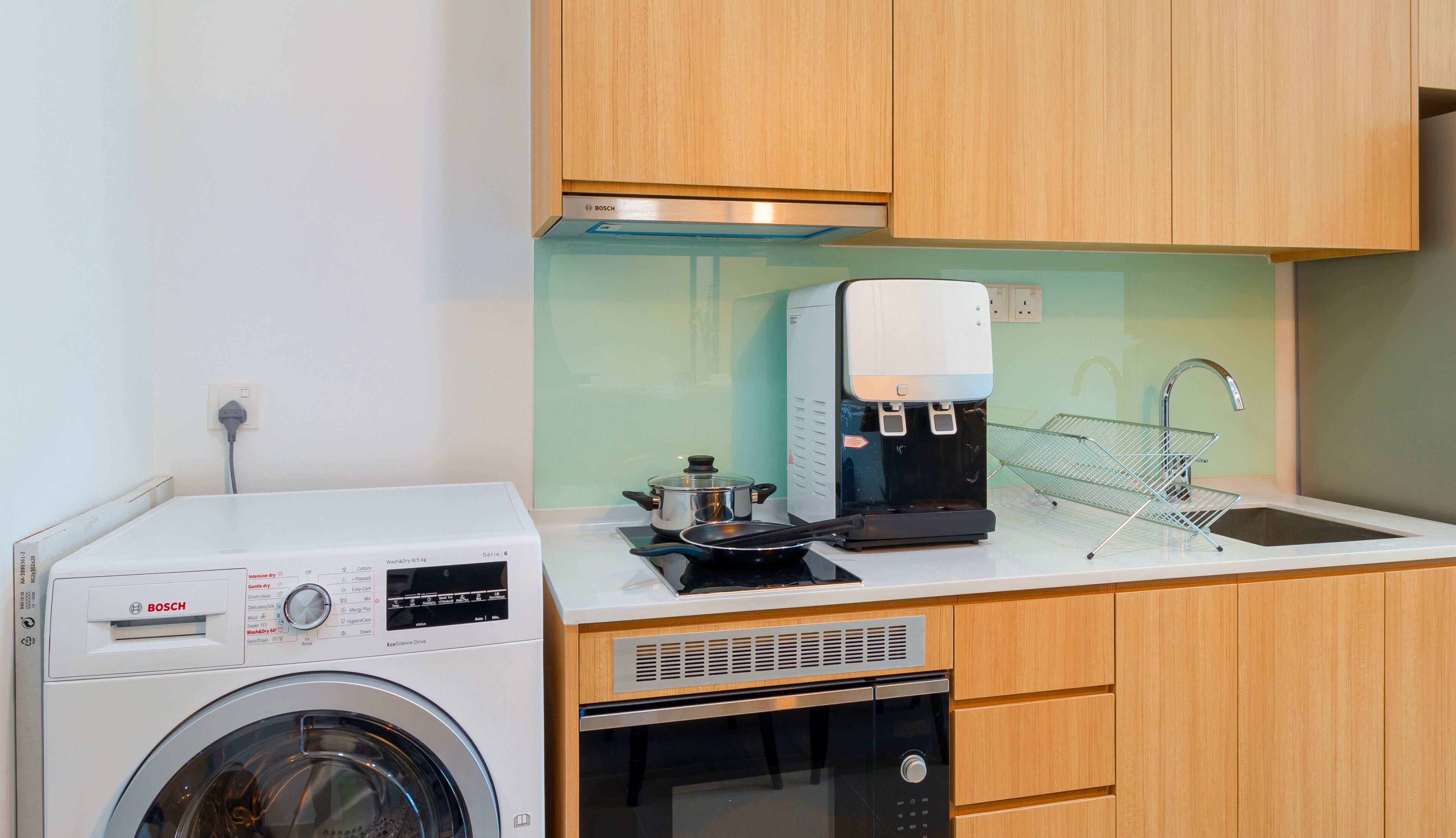 Una cocina compacta con lavadora Bosch, cafetera y lavavajillas.