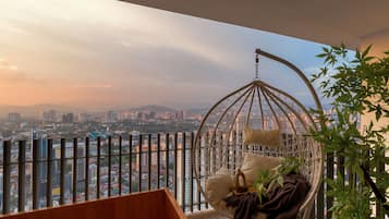 Una habitación con una silla colgante, vistas a un paisaje urbano y una planta.