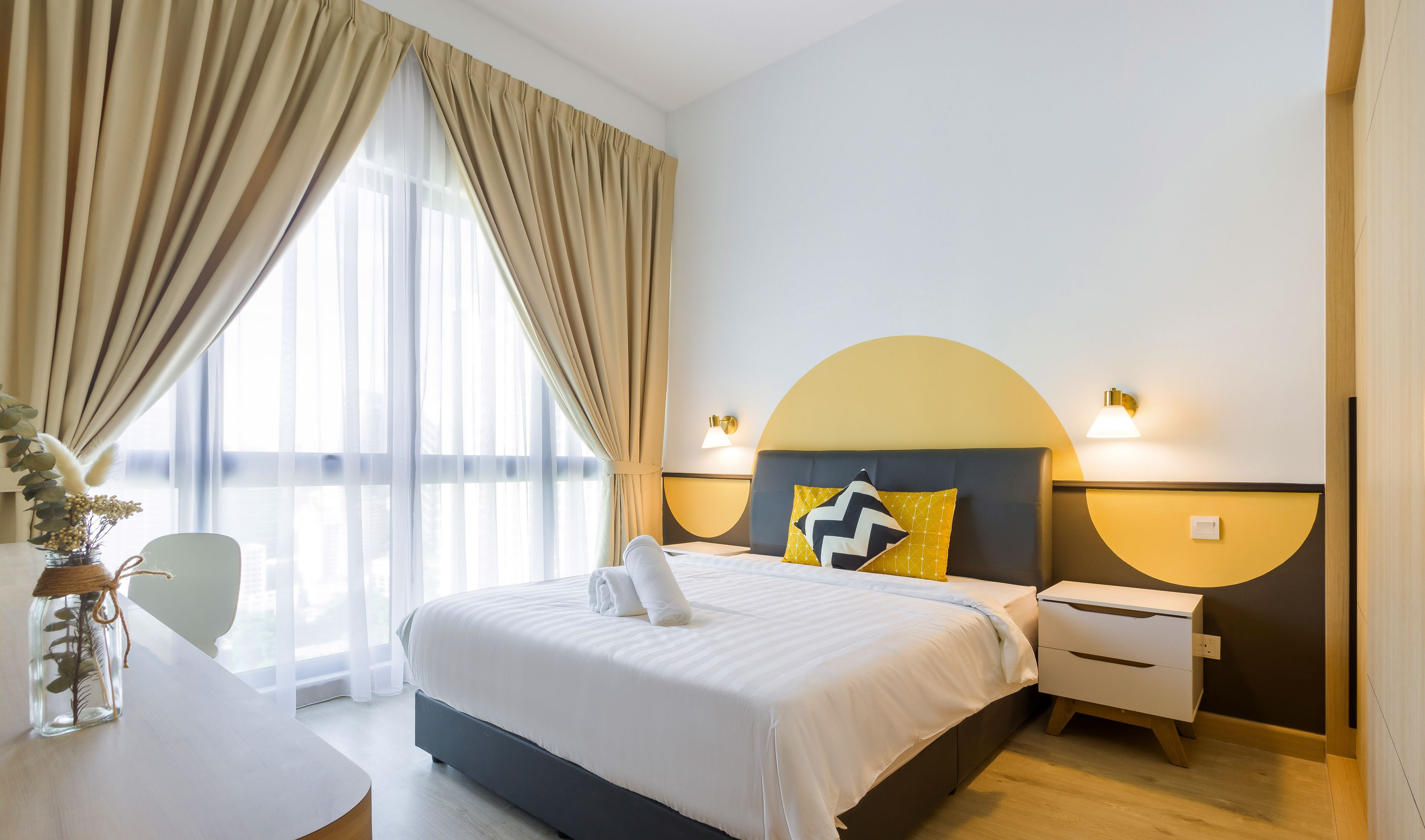 A hotel room with a large bed, a bedside table, a nightstand, and a view of the outdoors.
