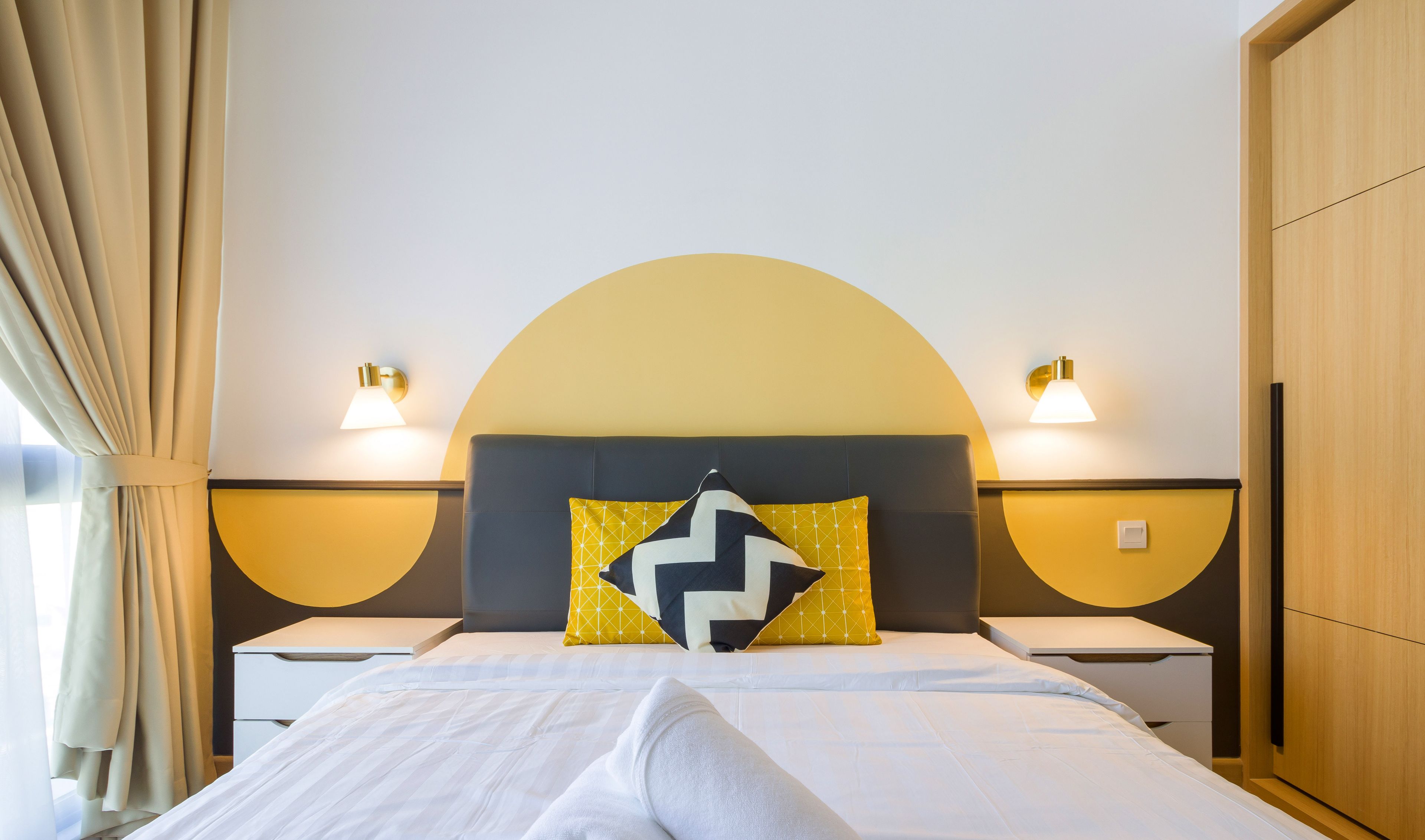 Ein Hotelzimmer mit Bett, Nachttisch, Lampe und Wandleuchte.