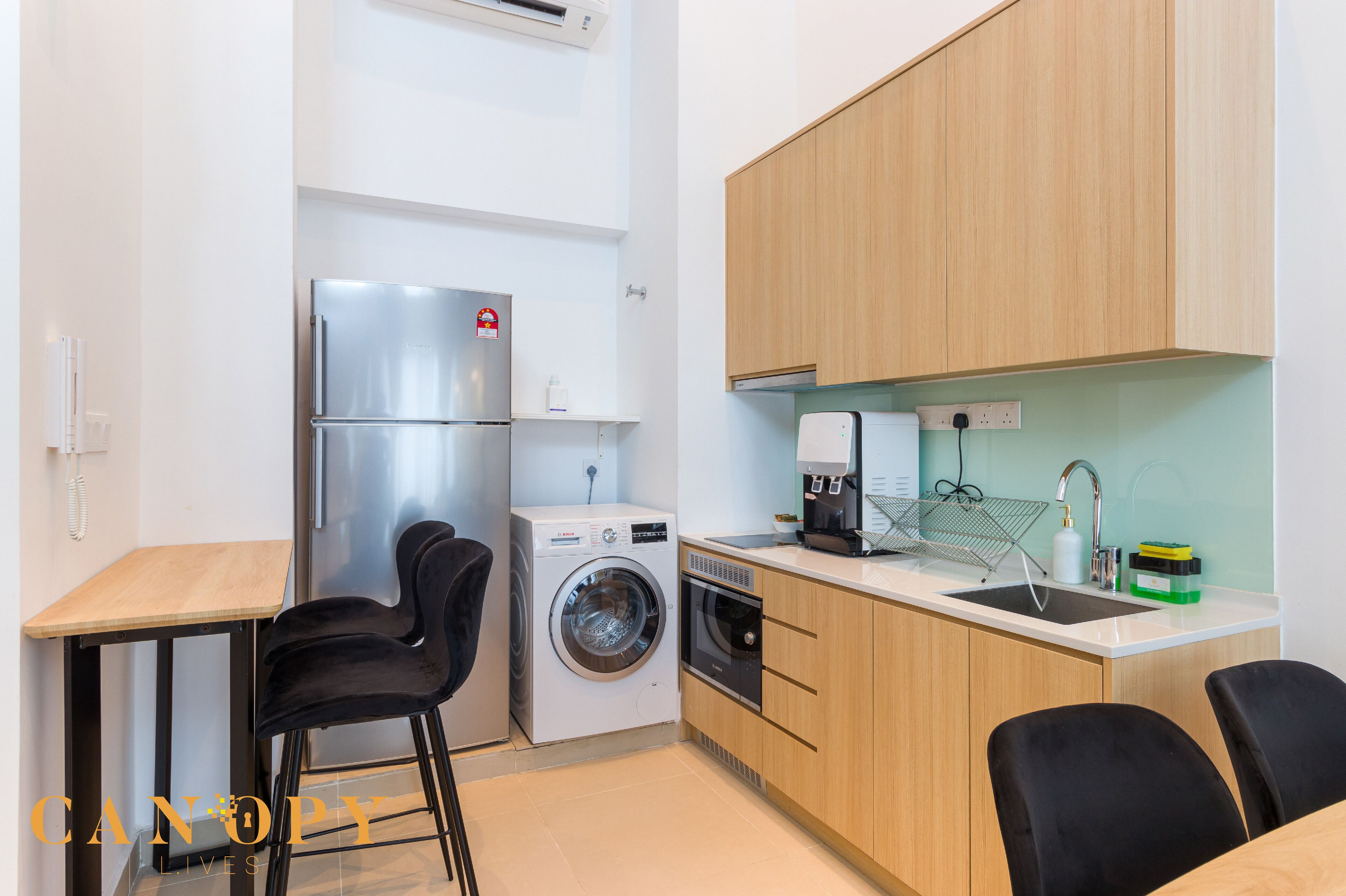 A compact kitchen with a washing machine, a refrigerator, a coffee maker, and a sink.
