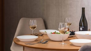 A dining table set with white plates, bowls, and wine glasses, accompanied by cutlery and a bottle of wine. - Fleur Sanno (Osaka)