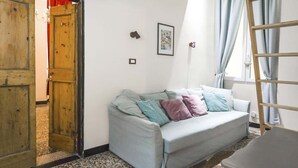 Una habitación con un sofá azul claro, una puerta de madera, una escalera y un cuadro en la pared.