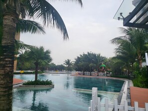 Ein Swimmingpool, umgeben von Palmen und einem weißen Zaun.