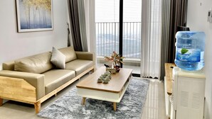 A modern living room with a sofa, coffee table, and a large window with curtains. - Vinhomes D'Capitale Ha Noi-Gem Apartment (Hanoi)