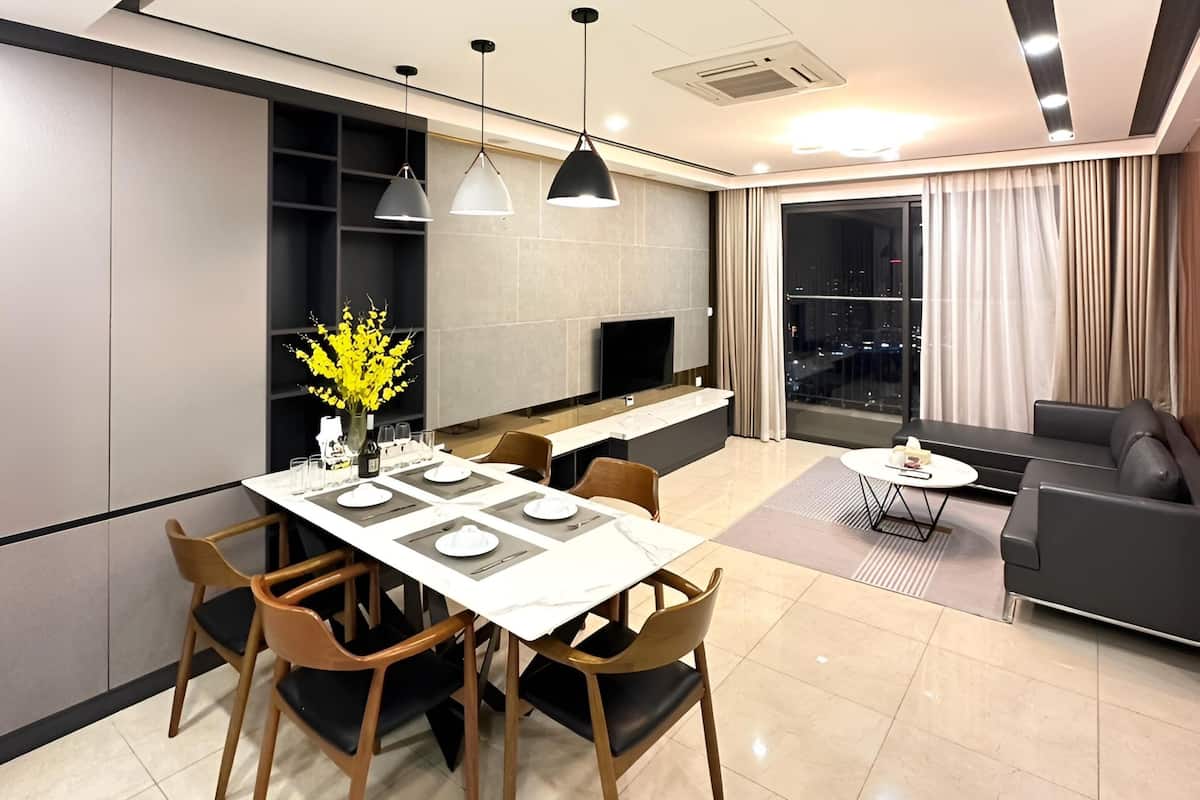 A modern living room with a dining area, a sofa, and a TV.