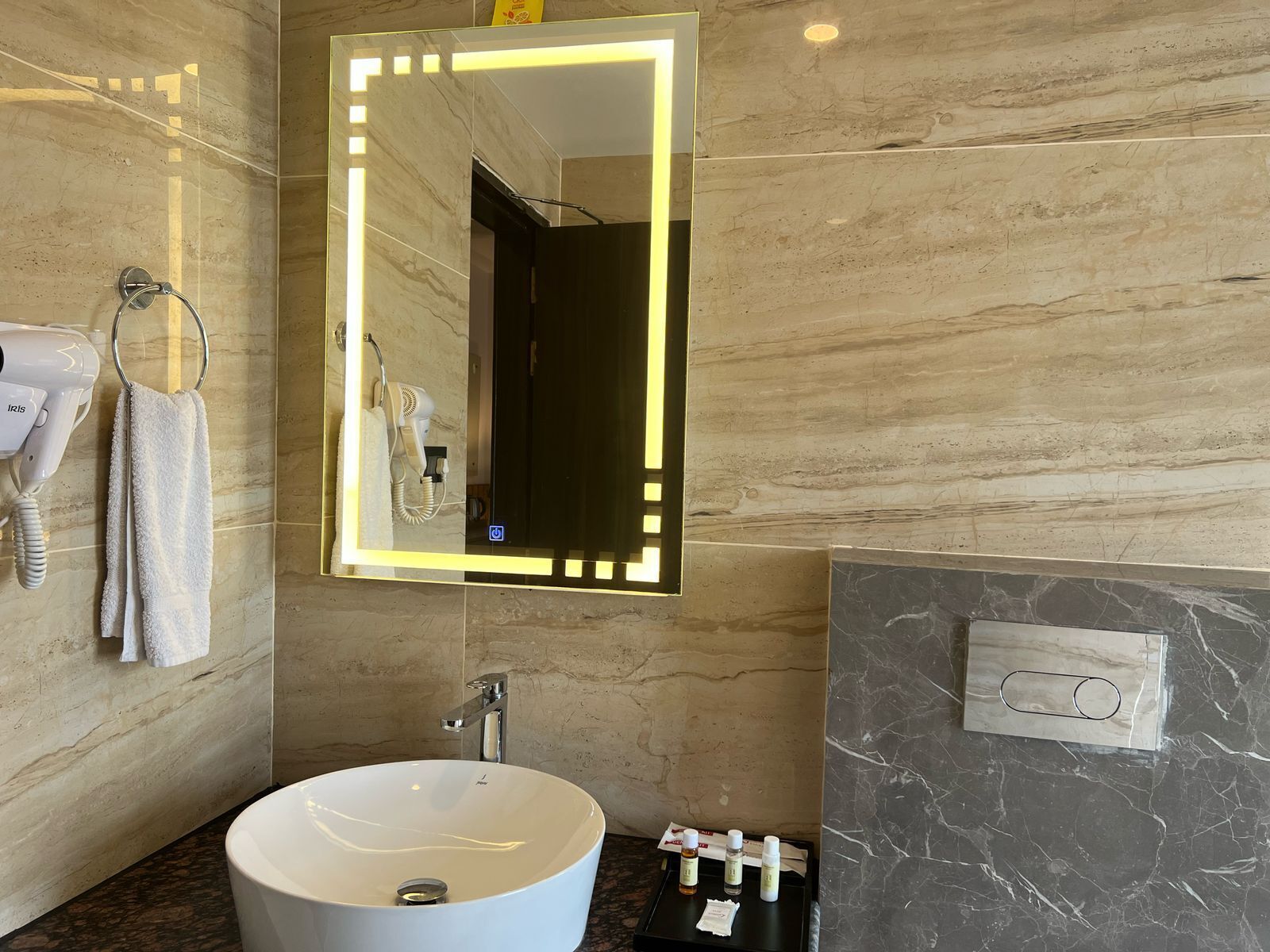 A bathroom with a large mirror, a sink, a towel rack, and a hairdryer.