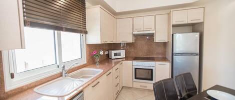 A compact kitchen with a sink, microwave, oven, and refrigerator.