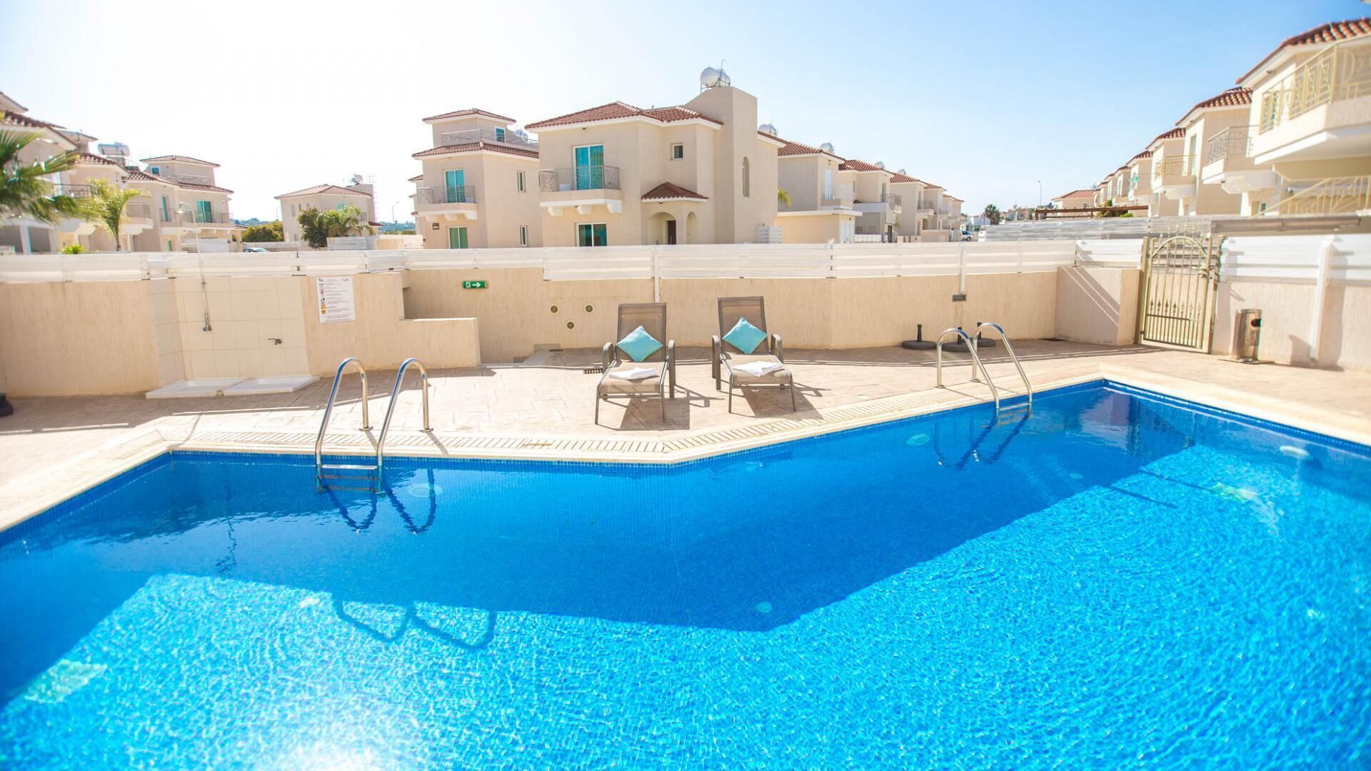 A swimming pool with lounge chairs and a view of residential buildings.