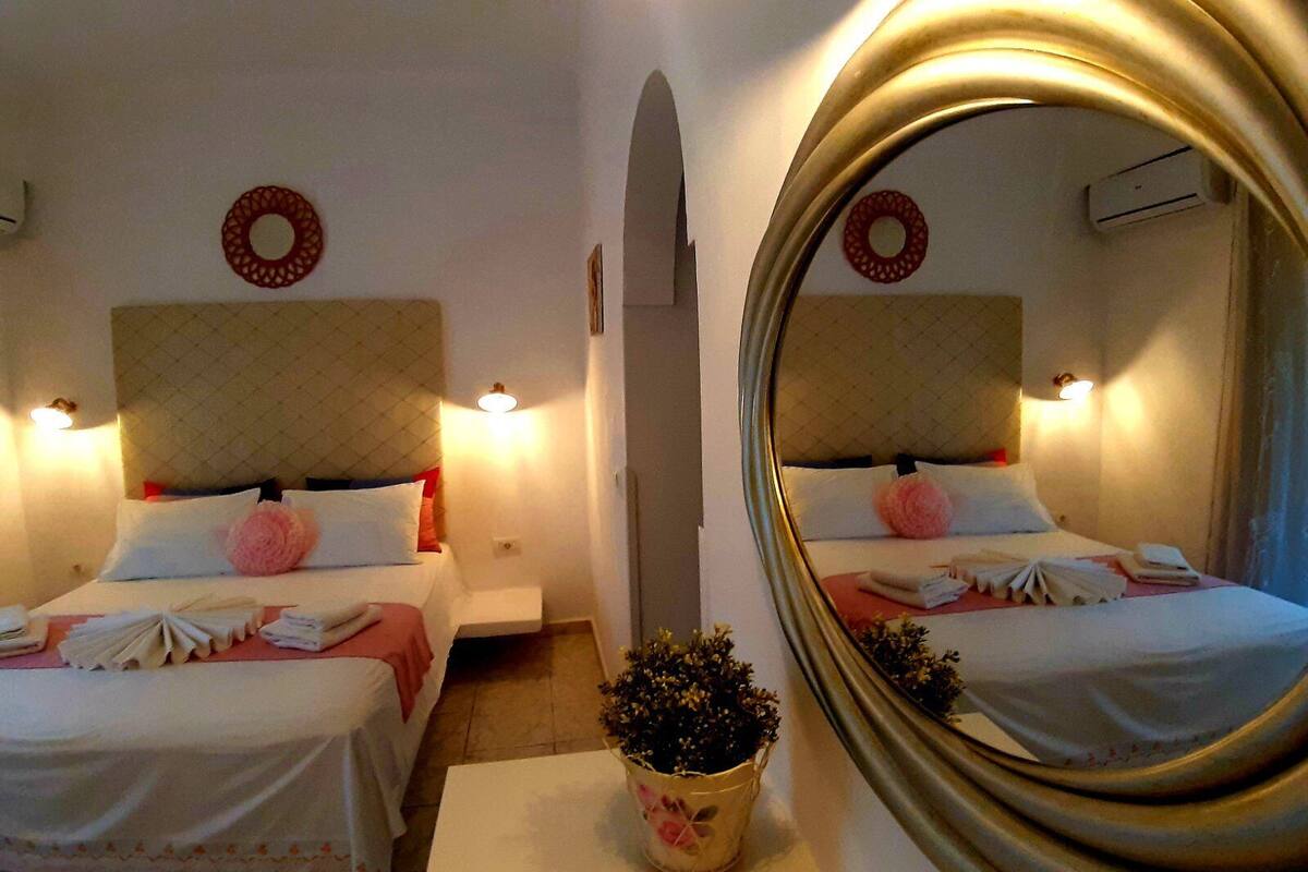 A hotel room with two beds, a large mirror, a potted plant, and a small table.