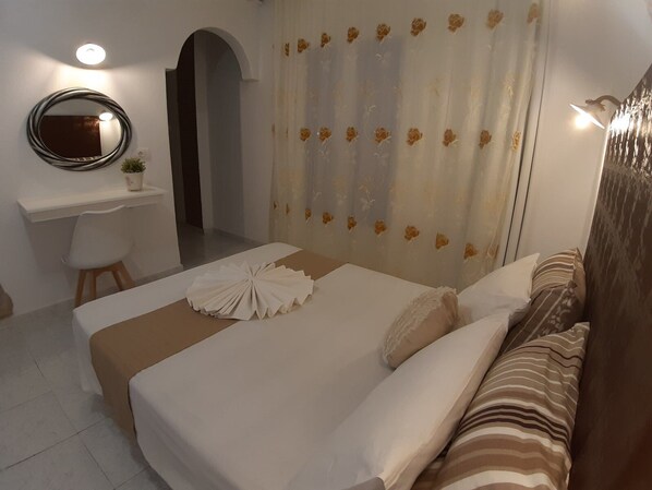 Une chambre d’hôtel avec un lit, un bureau et un miroir.