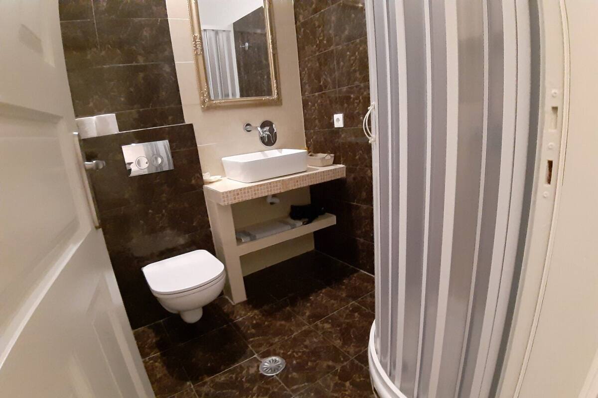 A bathroom with a white toilet, a sink with a mirror above it, and a shower area with a striped curtain.