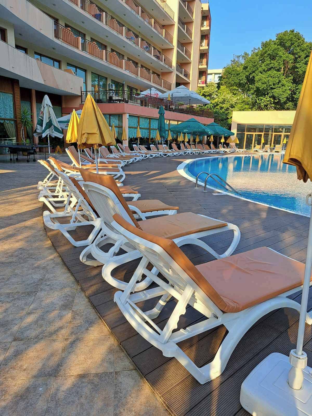 A poolside area with sun loungers, umbrellas, and a swimming pool.