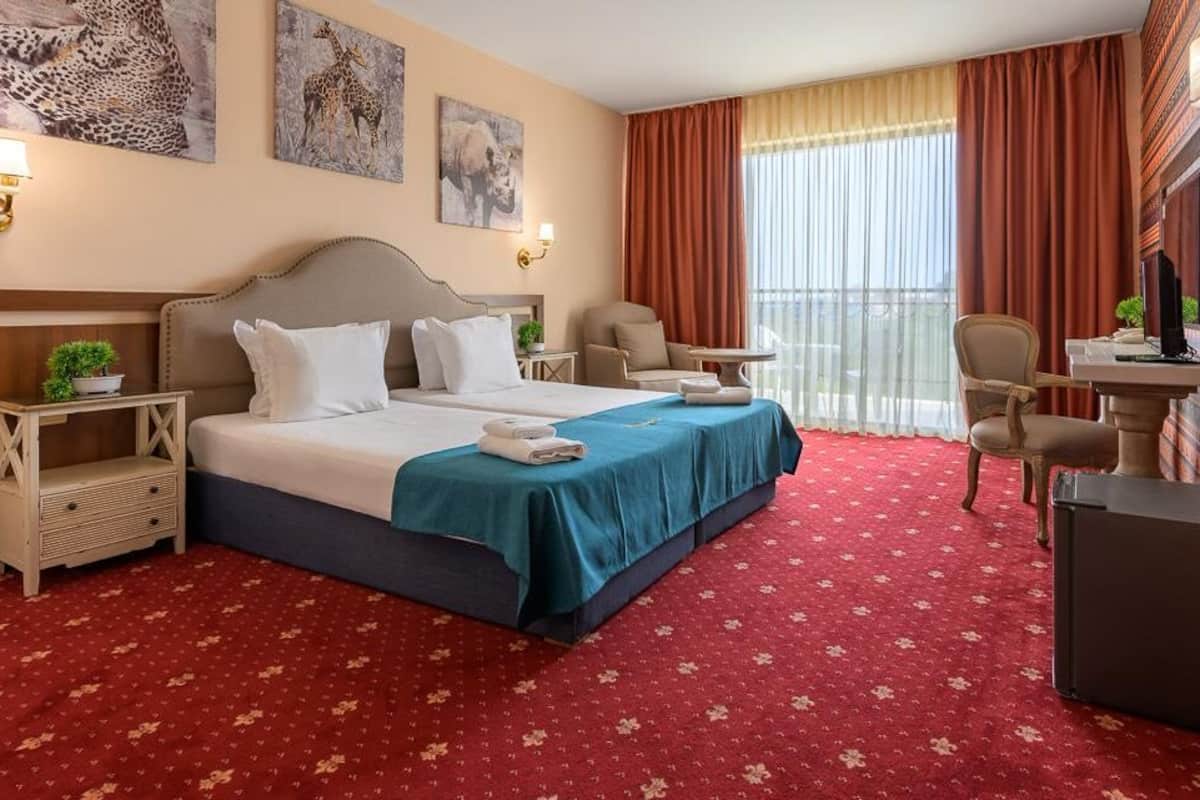 A hotel room with a large bed, two bedside tables, a desk, and a chair.