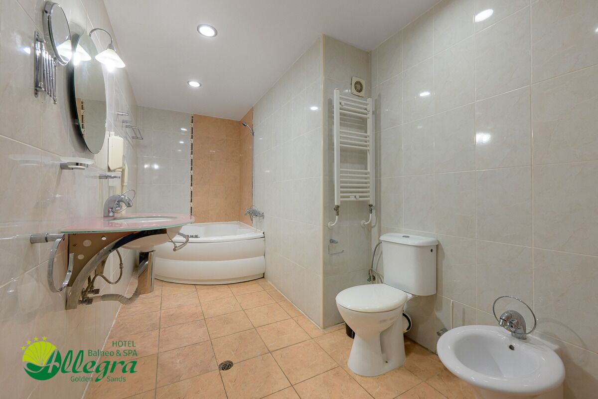 A modern bathroom with a bathtub, toilet, bidet, and vanity.