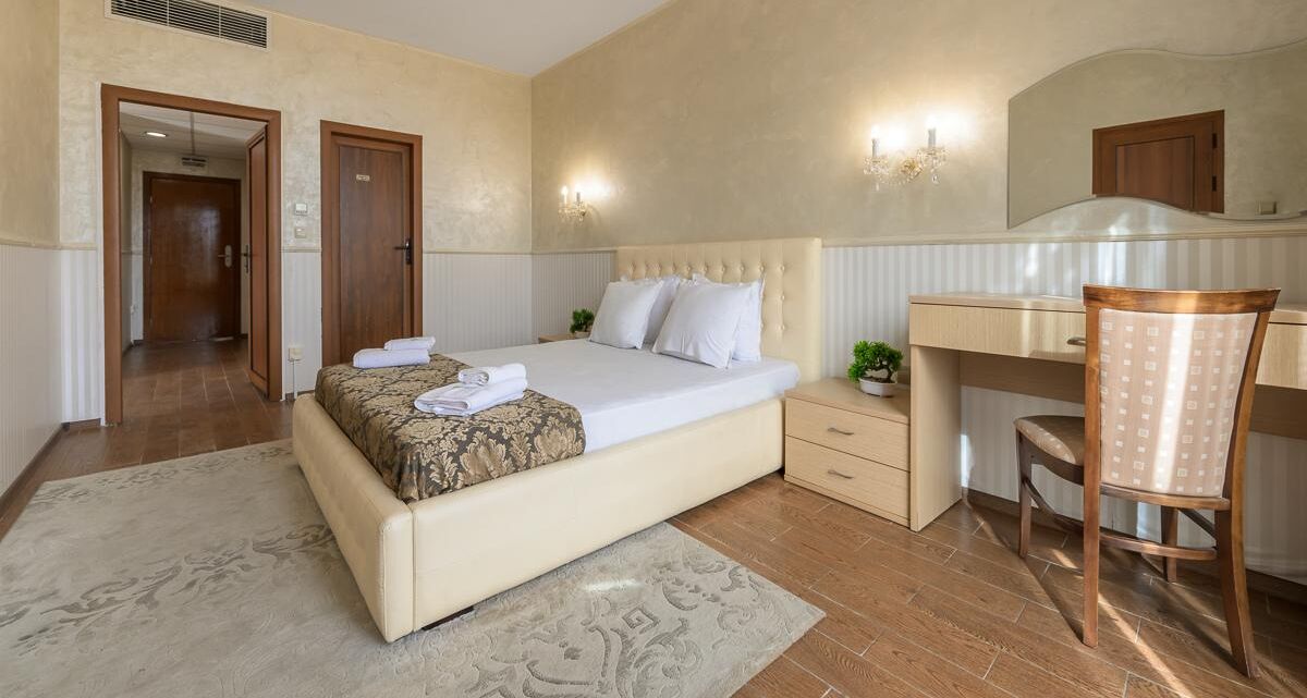 A bedroom with a bed, bedside table, chair, and desk.