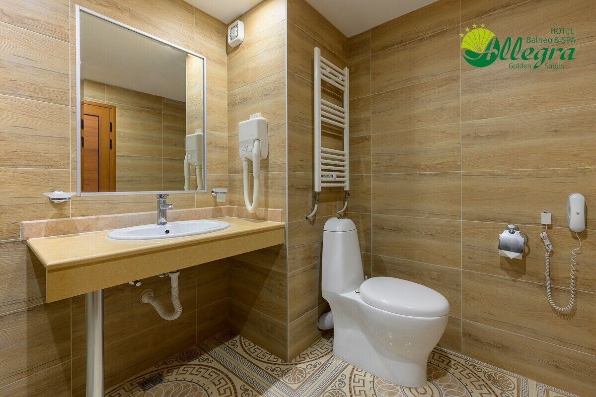 Une salle de bain moderne avec un plancher en bois, un lavabo avec un miroir, des toilettes et un porte-serviettes.