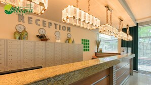 A hotel reception area with a marble counter, multiple clocks, and a large chandelier. - Allegra Balneo & SPA (Golden Sands)