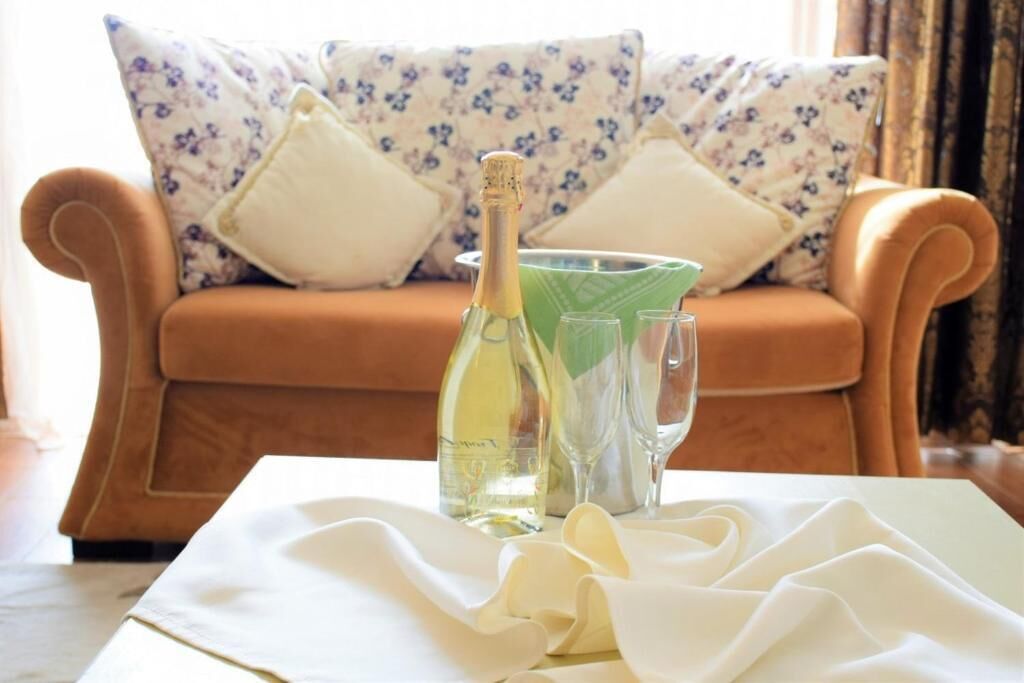 Une bouteille de champagne, deux verres et une bouteille verte sur une table recouverte d’une nappe blanche.