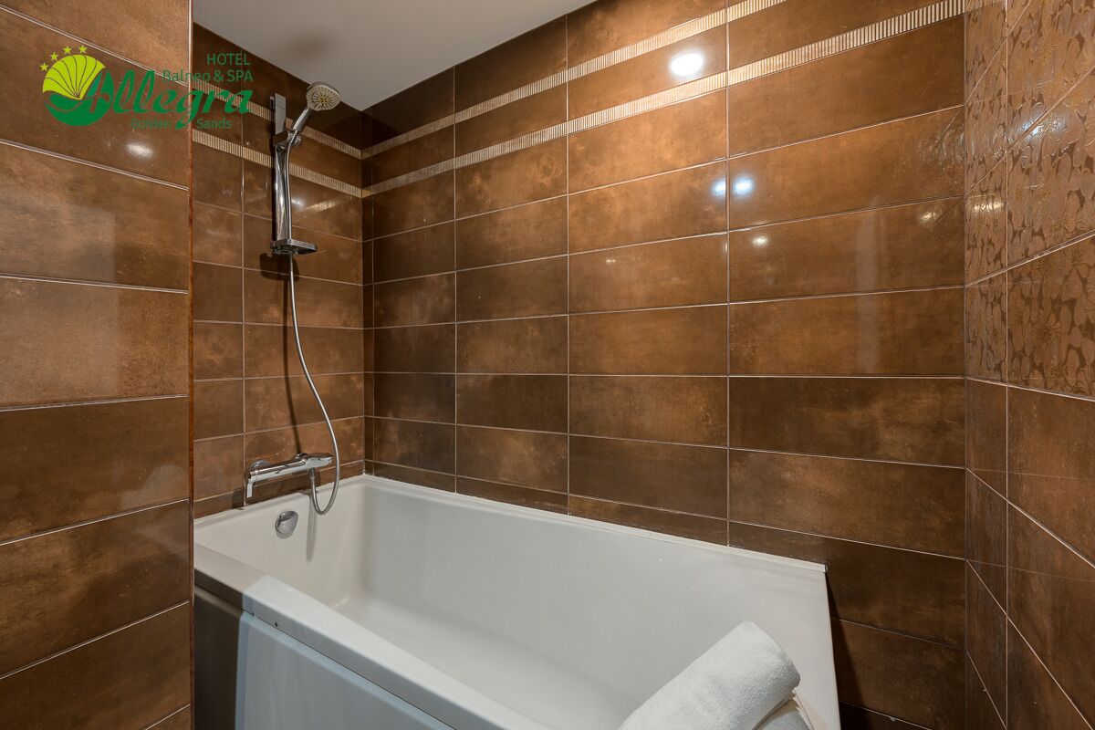 Un baño moderno con bañera, ducha y paredes de azulejos marrones.