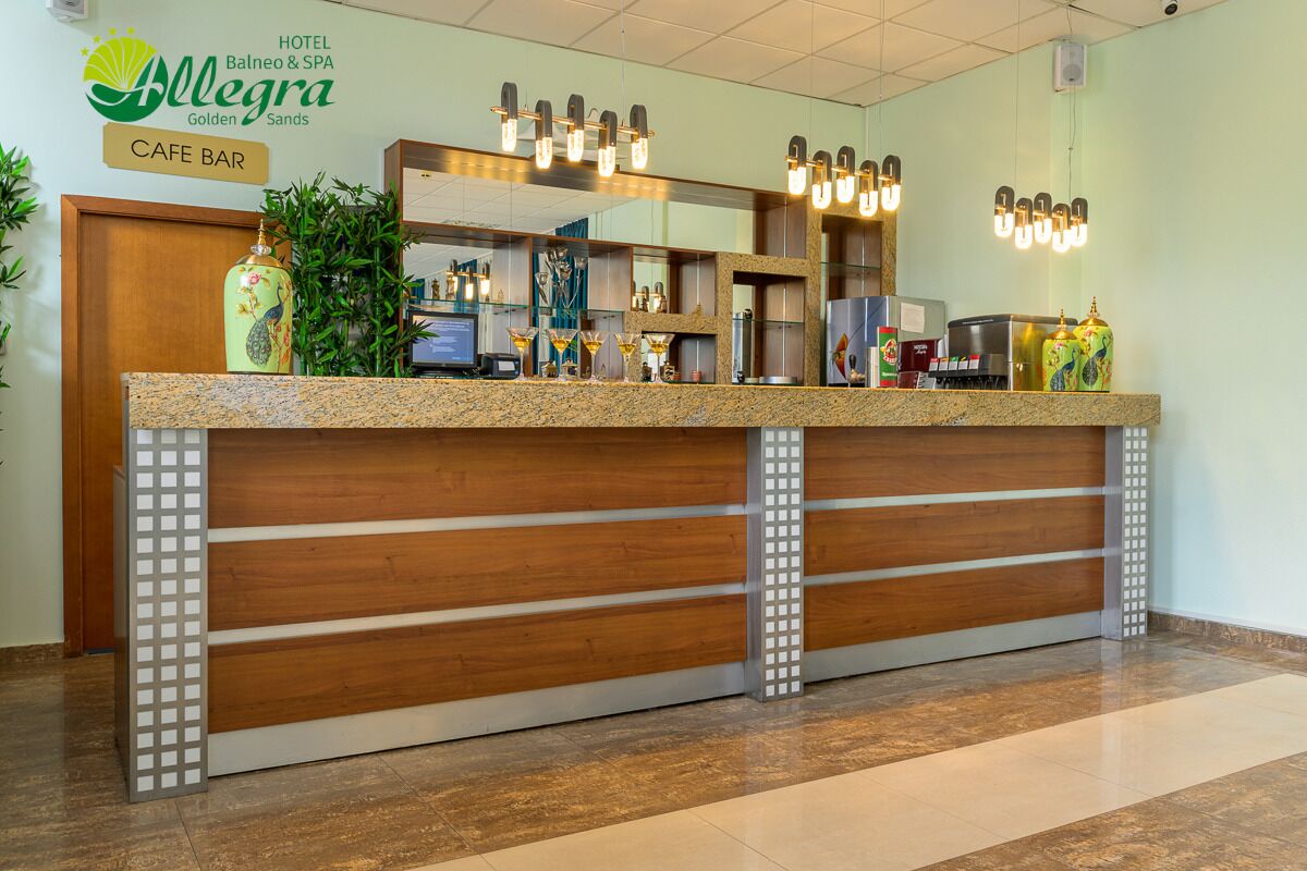 A hotel reception desk with a wooden design, a cafe bar sign, and a mirror above the counter.