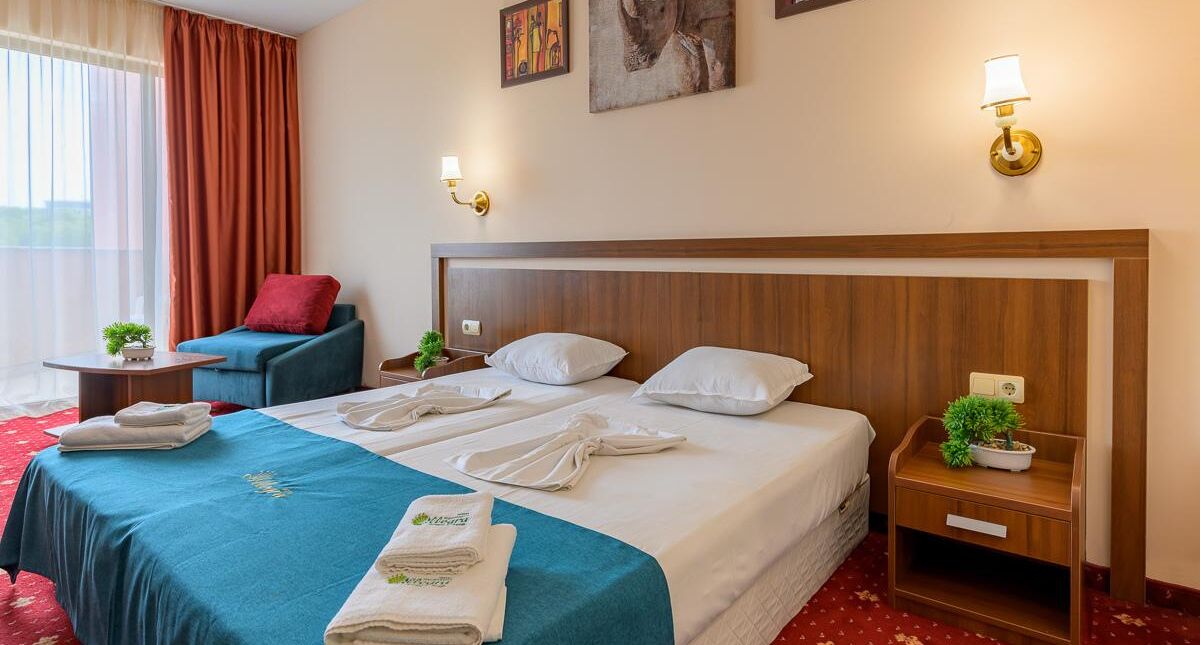 A hotel room with a large bed, a sofa, a small table, and a nightstand.