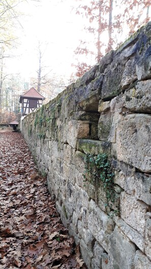 A stone wall with a small wooden structure in the background.