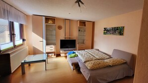 A bedroom with a bed, a TV, a desk, and a wardrobe.