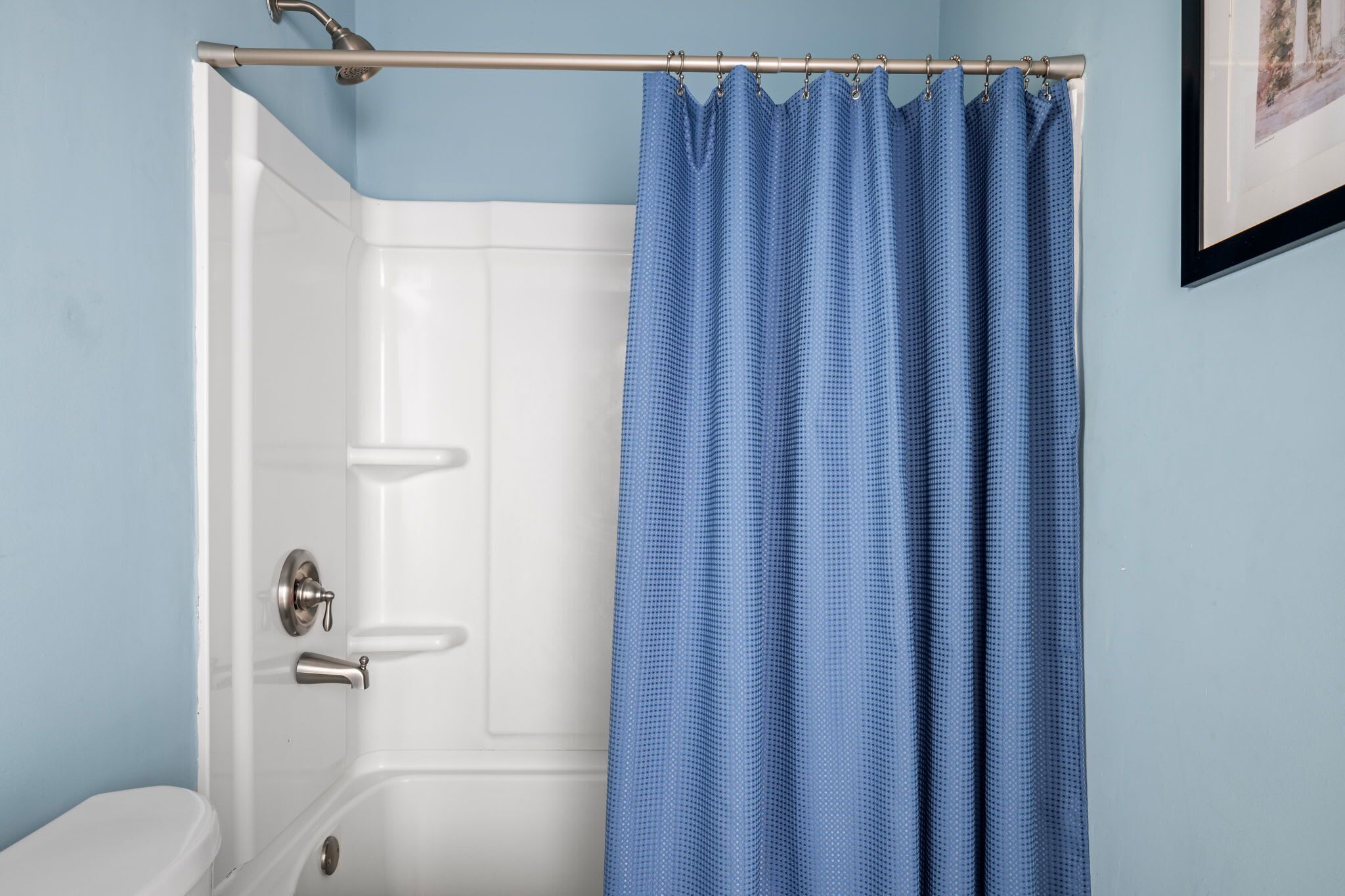 Une salle de bain avec une baignoire blanche, un rideau de douche et des toilettes.