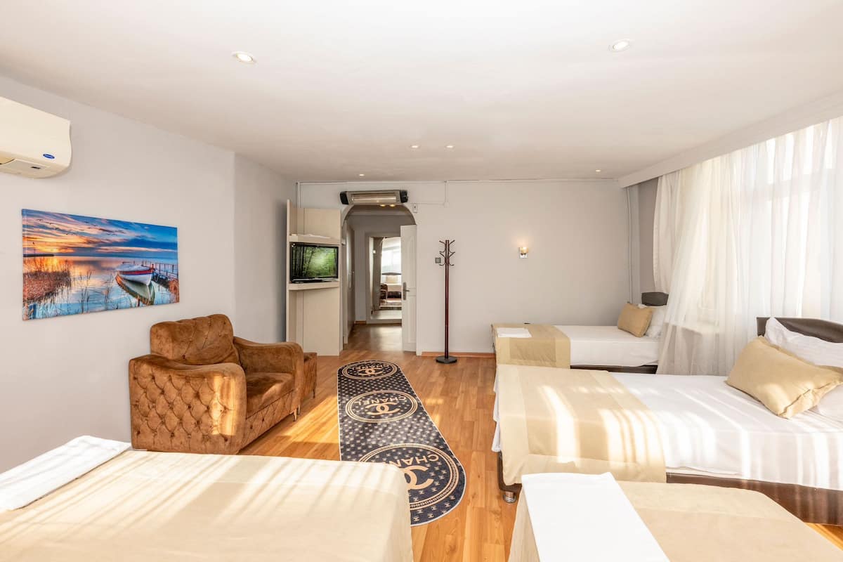 Una habitación de hotel con dos camas, un sofá, un televisor y un cuadro en la pared.