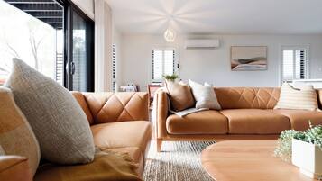 A modern living room with a brown leather sofa, a wooden coffee table, and a woven rug.