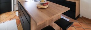 Eine Küche mit einer Holzarbeitsplatte, einem schwarzen Stuhl und einem gefliesten Boden.