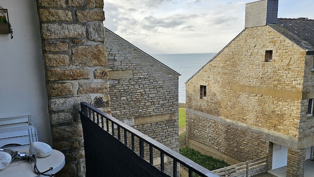 Ein Steinhaus mit einem Balkon, der auf einen Innenhof und ein Gewässer blickt.