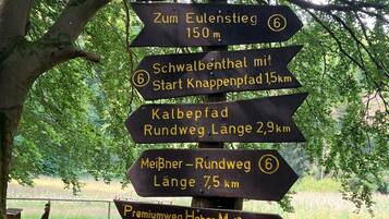 A directional signpost in a park with multiple arrows pointing to various destinations and distances.