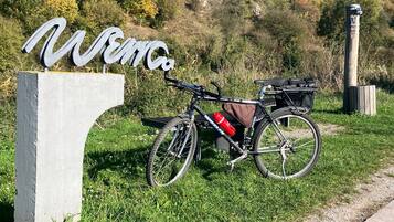 A bicycle parked next to a sign with the word "Welcome" on a grassy area with a hilly background.