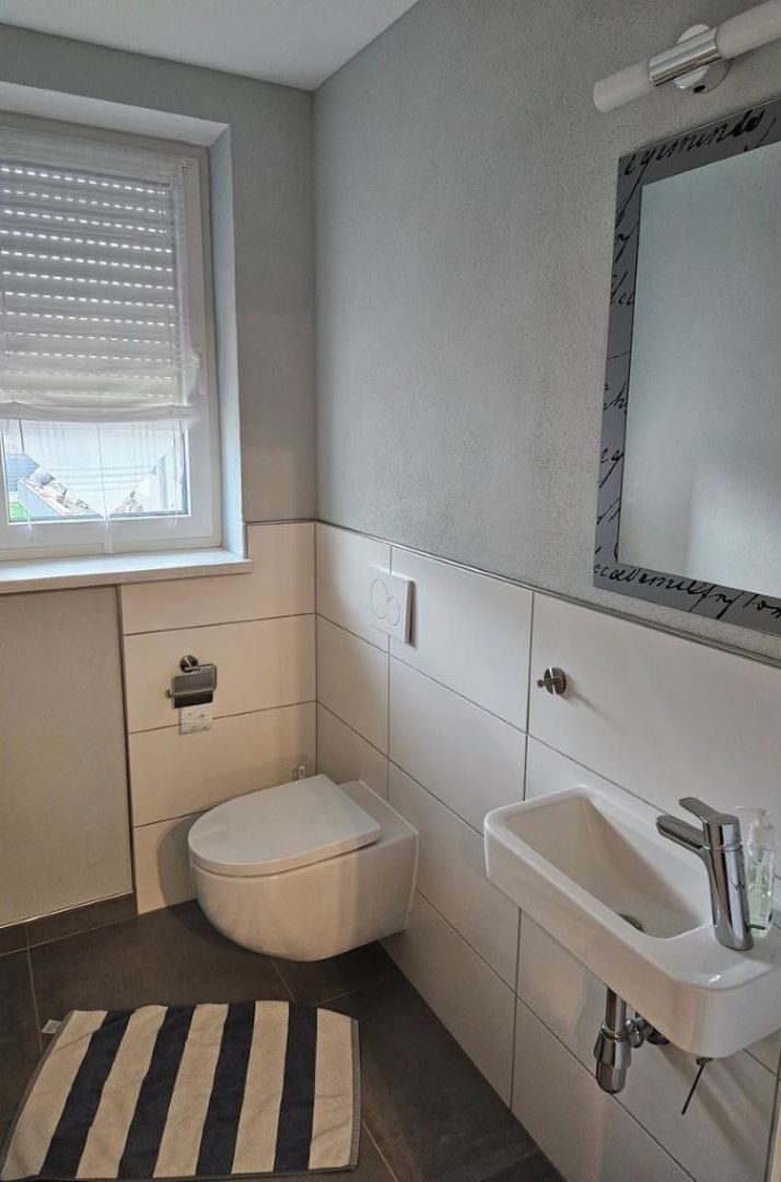 A small bathroom with a toilet, sink, and window.
