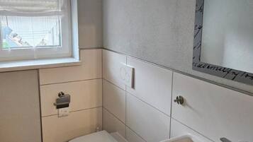A small bathroom with a toilet, sink, and window.