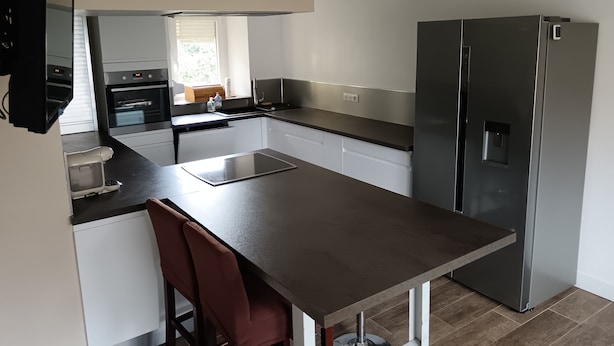 A modern kitchen with a central island, stainless steel appliances, and white cabinetry. - Village house  (Merxheim)
