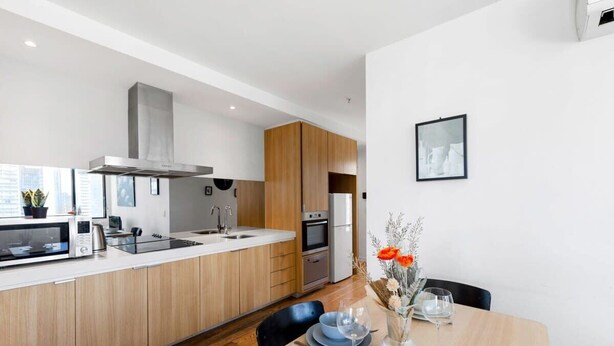 Une cuisine moderne avec des meubles en bois, une hotte en acier inoxydable et un four encastré.