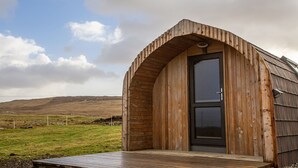 A wooden cabin with a black door and a wooden deck. - Heisgeir (Isle of North Uist)