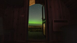 A wooden door leading to a room with a view of the night sky and a distant landscape. - Heisgeir (Isle of North Uist)