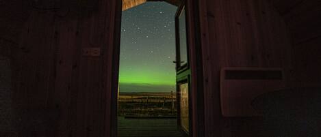 A wooden door leading to a room with a view of the night sky and a distant landscape.