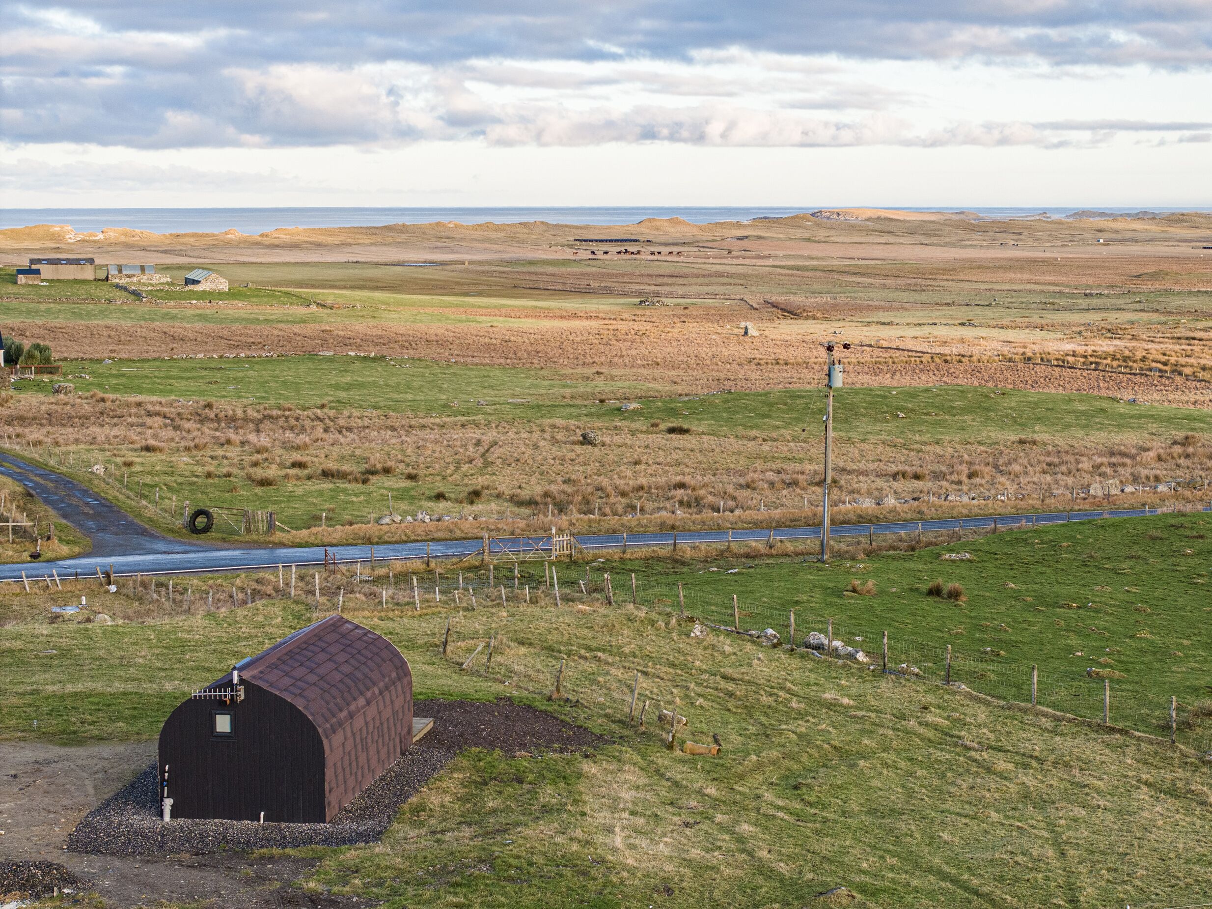 A rural landscape with a barn, a road, and open fields.