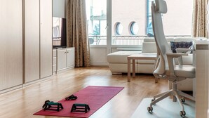 A modern living room with a sofa, a high chair, and exercise equipment on a red mat. - Fitness friendly studio apartment in Paradiso (Little Paradise) (Paradiso)