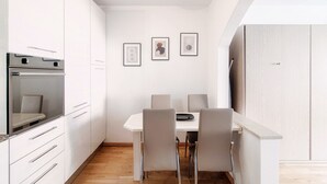 A modern kitchen with white cabinetry, a built-in oven, and a dining area with a white table and four chairs. - Fitness friendly studio apartment in Paradiso (Little Paradise) (Paradiso)